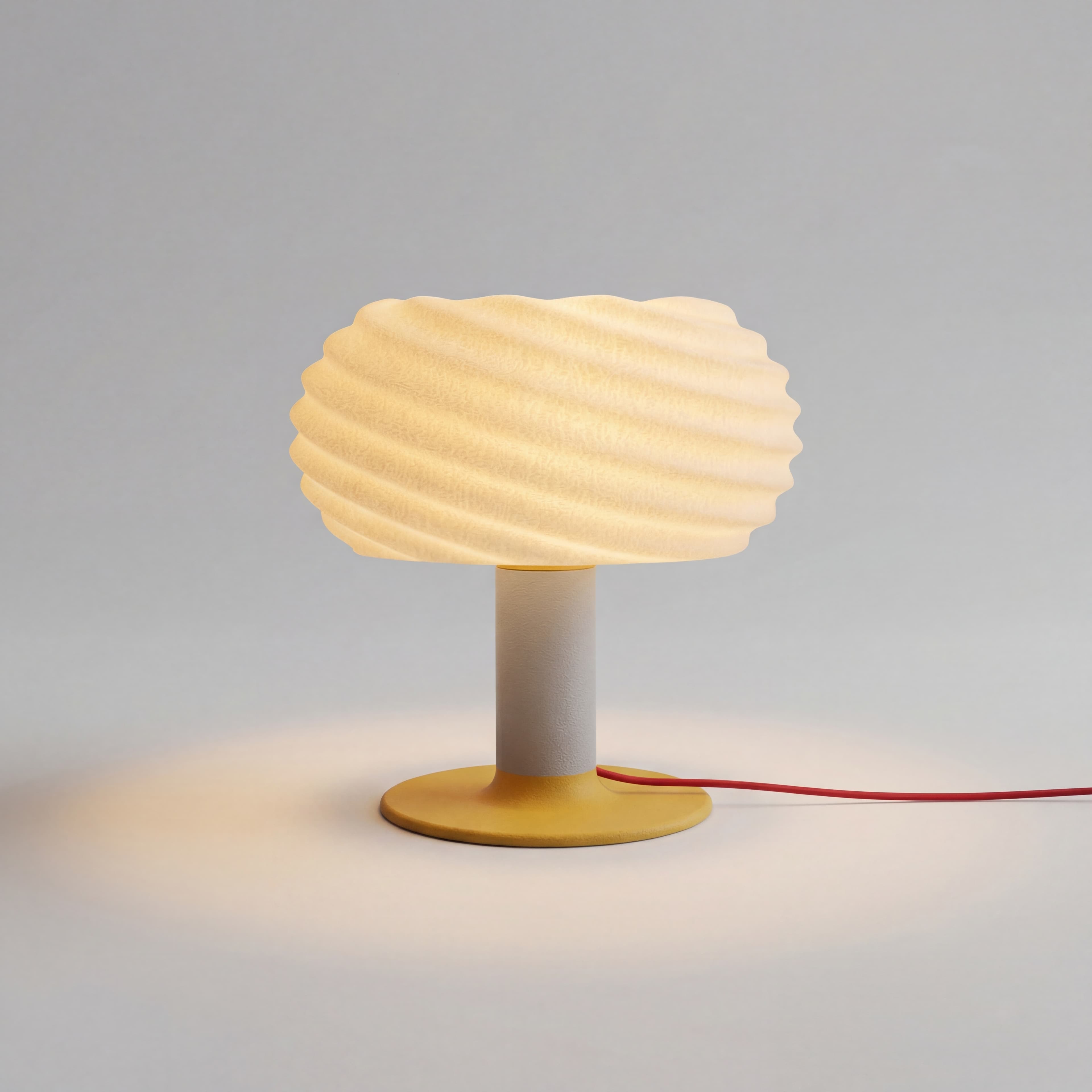 Mira wavy table lamp with cream shade, yellow base, and red cord on a minimalist surface